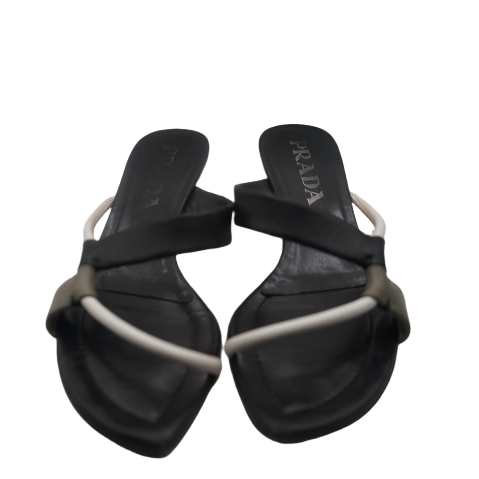  featuring black leather straps with a sleek white accent that crisscrosses over the top. The sandals have a minimalistic