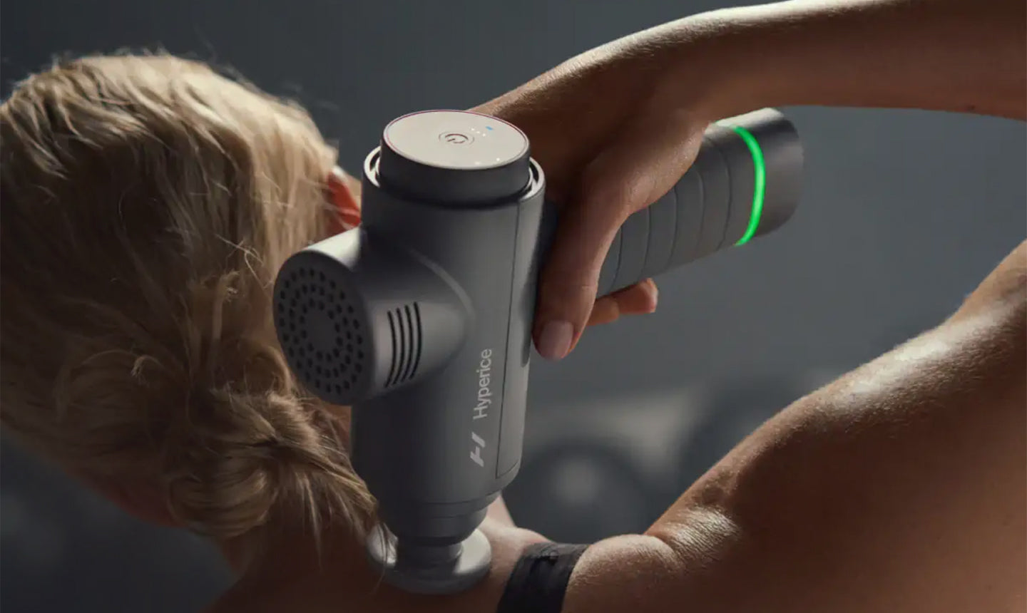 person using massage gun on shoulder
